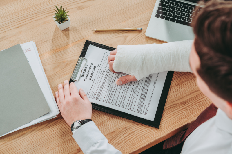 person with hand in cast filling out workers compensation form