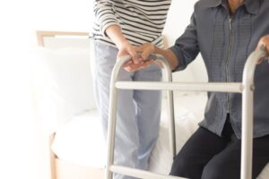 Training and rehabilitation process for walking, involving a stroke patient using a walker with the assistance of a caregiver.