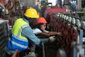 Factory mishap: Woman feel carpal tunnel pain, arm stuck. Male engineer aids. Emphasizing Safety First Aid. 