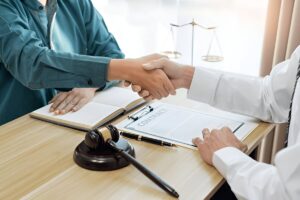 Workers comp lawyer reviewing a contract and shaking hands with a client in agreement.