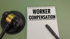 Worker Compensation Concept on Notebook with Judge Gavel Representing Employee Rights, Legal Settlement, Workplace Injury Claim, Financial Compensation, and Labor Law Protection. 