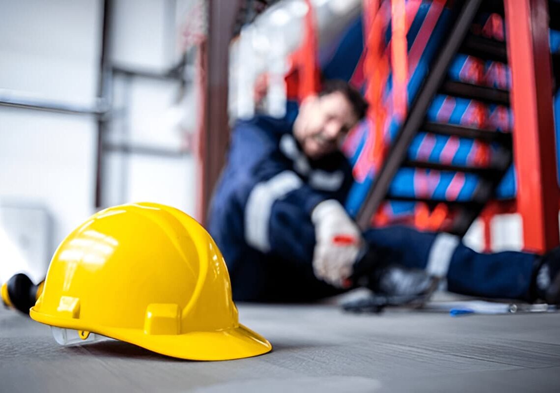 Safety at work. Close up view on hardhat and injured factory worker in background.